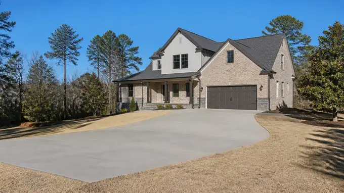 colored concrete installation completed by a local contractor at a brick-and-siding two-story home in Sandy Springs, GA, in clear late-morning sun.