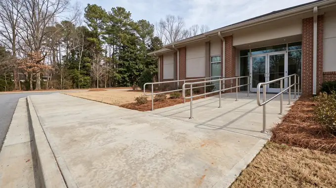 Concrete entry walk and ADA ramp at a medical office building in Sandy Springs, GA, under bright midday cloud.