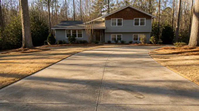 Concrete slab leveled with small patched holes from mudjacking at a grey split-level home in Sandy Springs, GA, in late afternoon light.