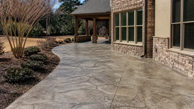 stained concrete installation completed by a local contractor at a stacked-stone and stucco home in Sandy Springs, GA, in full afternoon sun.